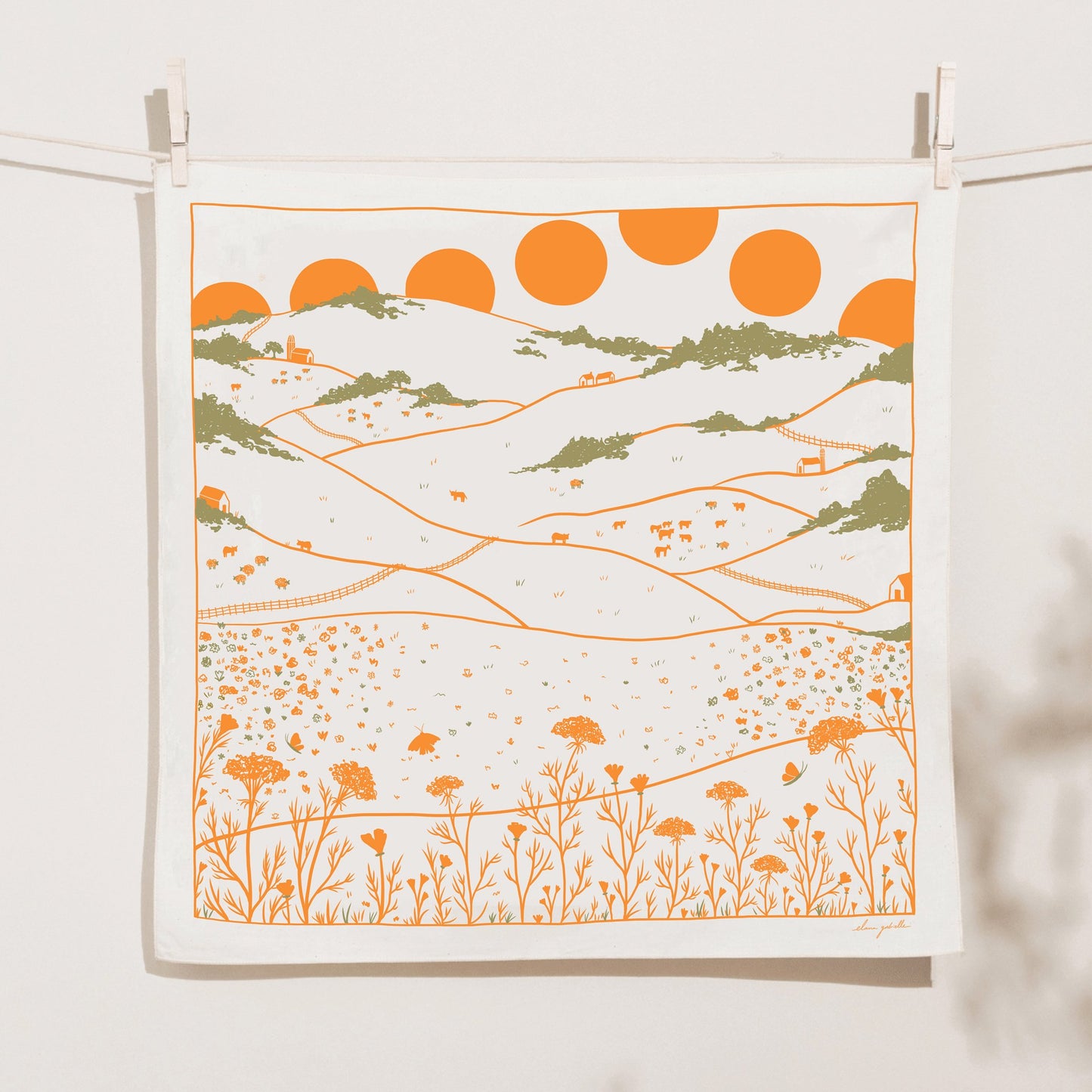 Illustrated bandana featuring an orange and green landscape with multiple suns setting over hills and valleys